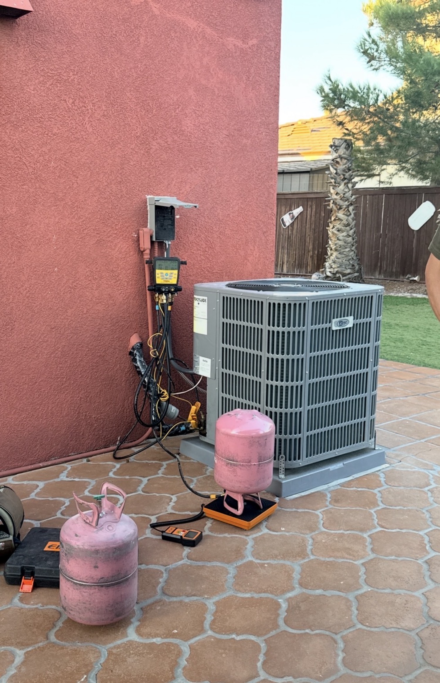 Gauges on an outdoor condenser while the system is being charged, refrigerant cylinder on a scale